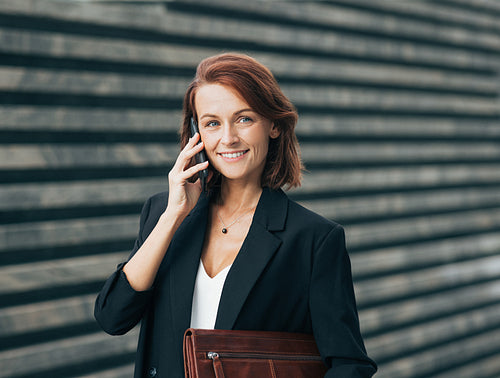 Smiling middle-aged businesswoman making a phone call and looking at the camera