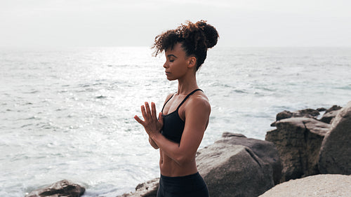 Female in sportswear meditating outdoors at the ocean