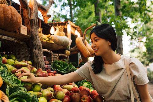 Woman at a farmers market with organic fruits and vegetables. Asian woman at a local outdoor market.