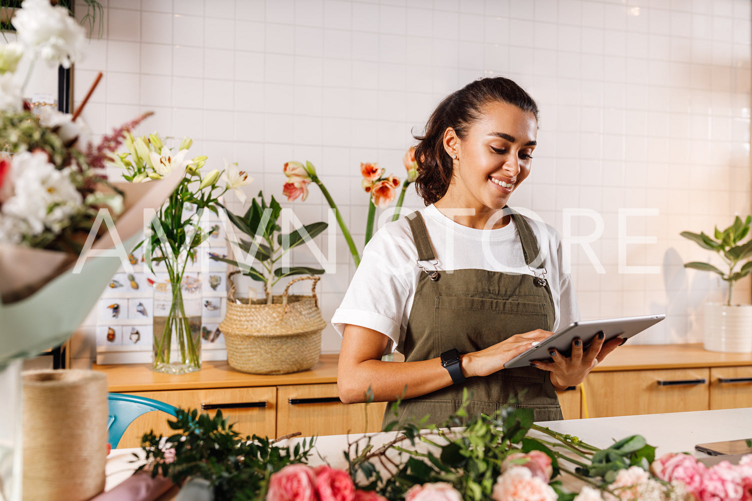 Young female florist making notes on a digital tablet. Woman checking online orders in shop.	