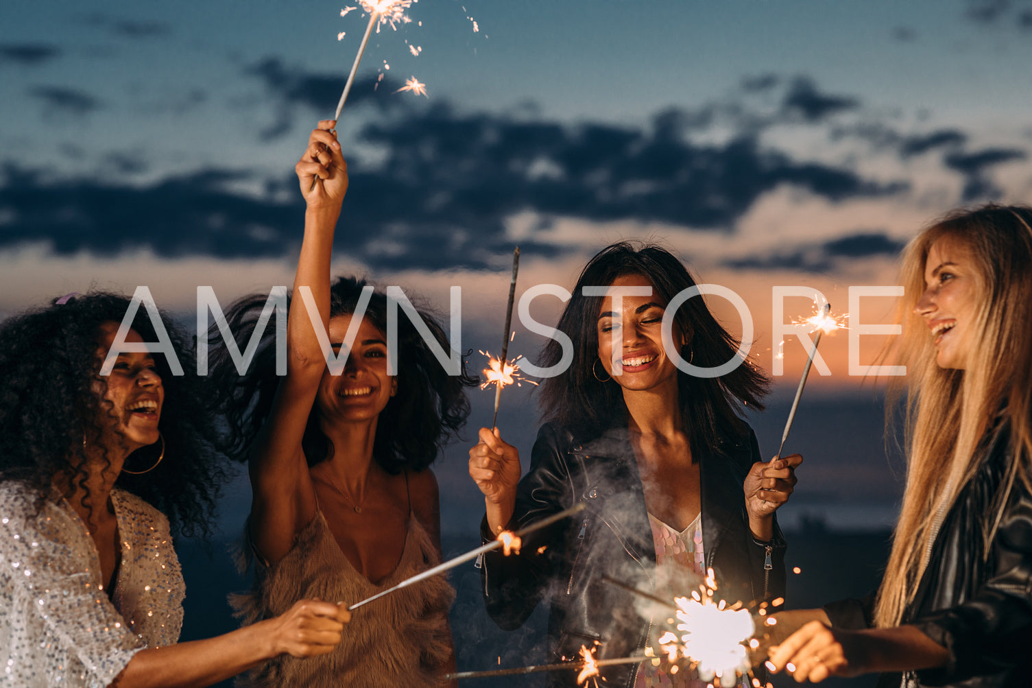 Four happy women celebrating at sunset with sparklers	