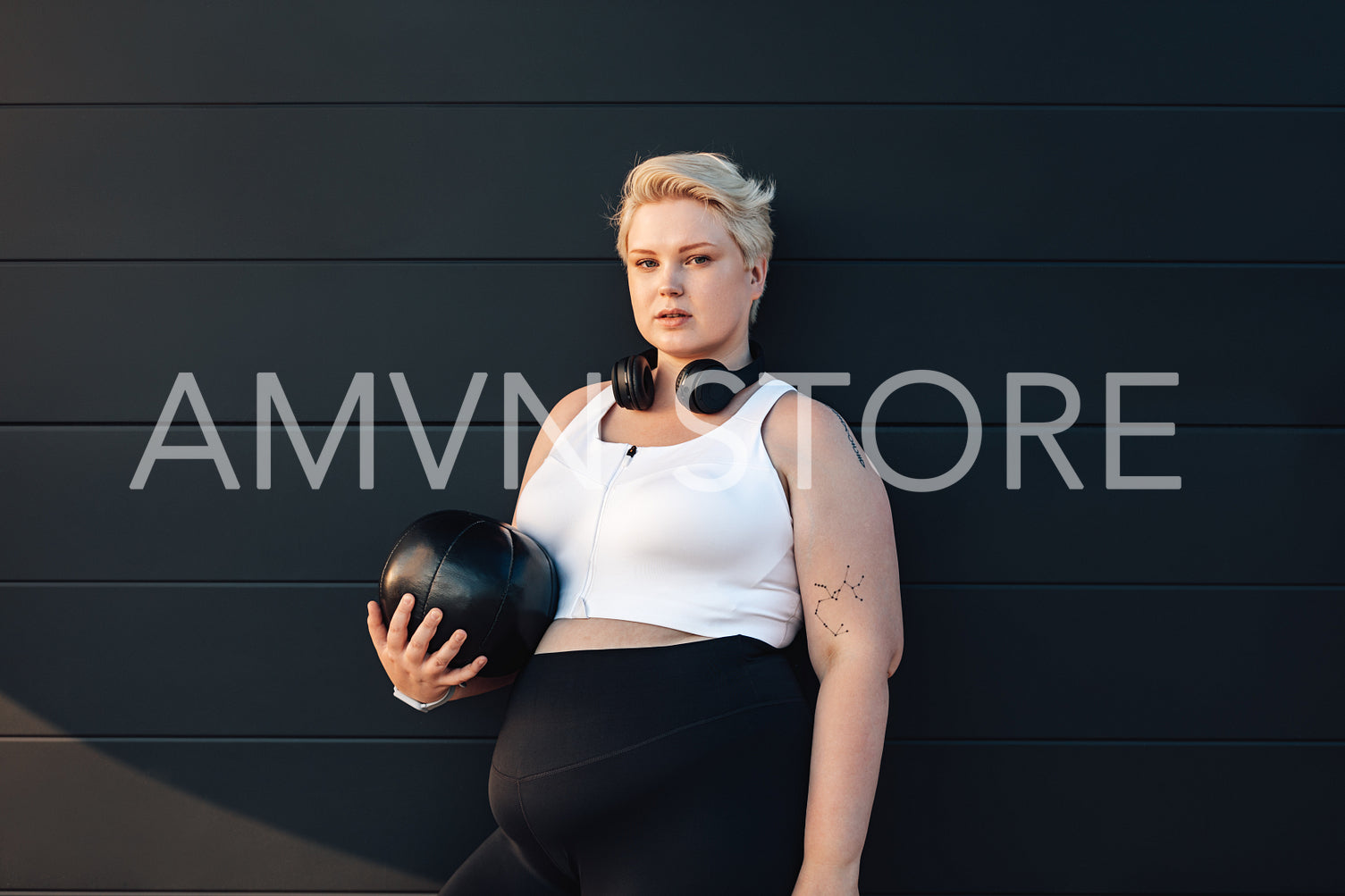 Young woman with a medicine ball at a black wall