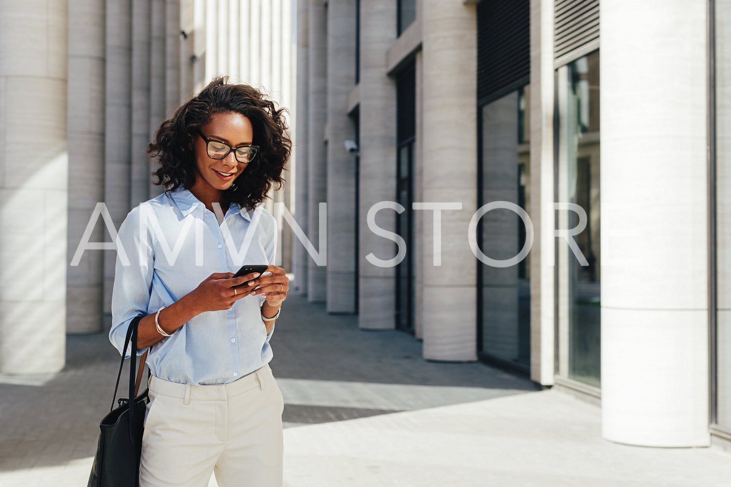 Woman texting from mobile phone near a office building	