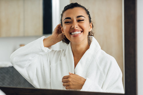 Happy woman with closed eyes standing in front of a mirror. Positive female standing in bathroom.