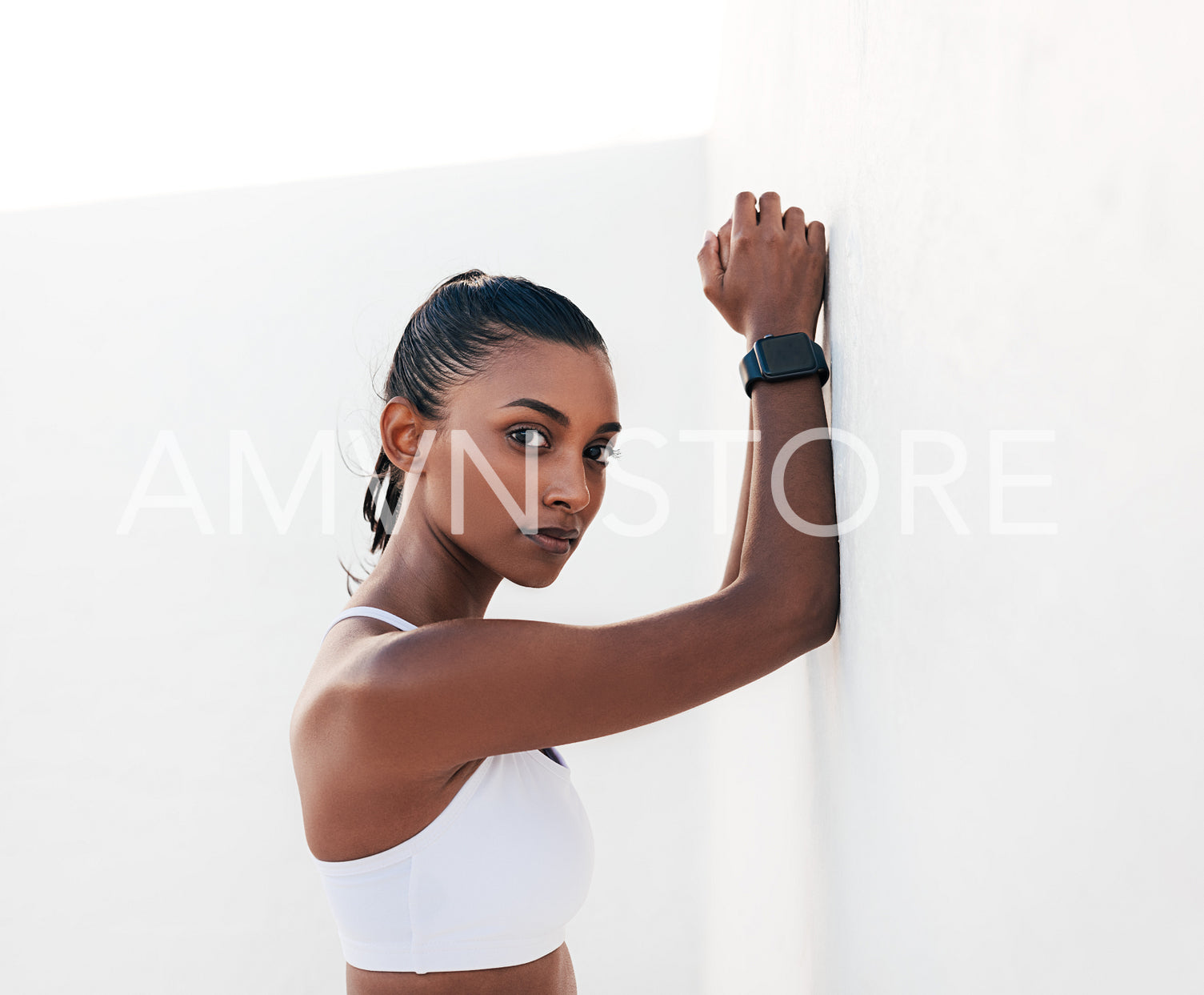 Slim athlete leaning white wall looking at the camera