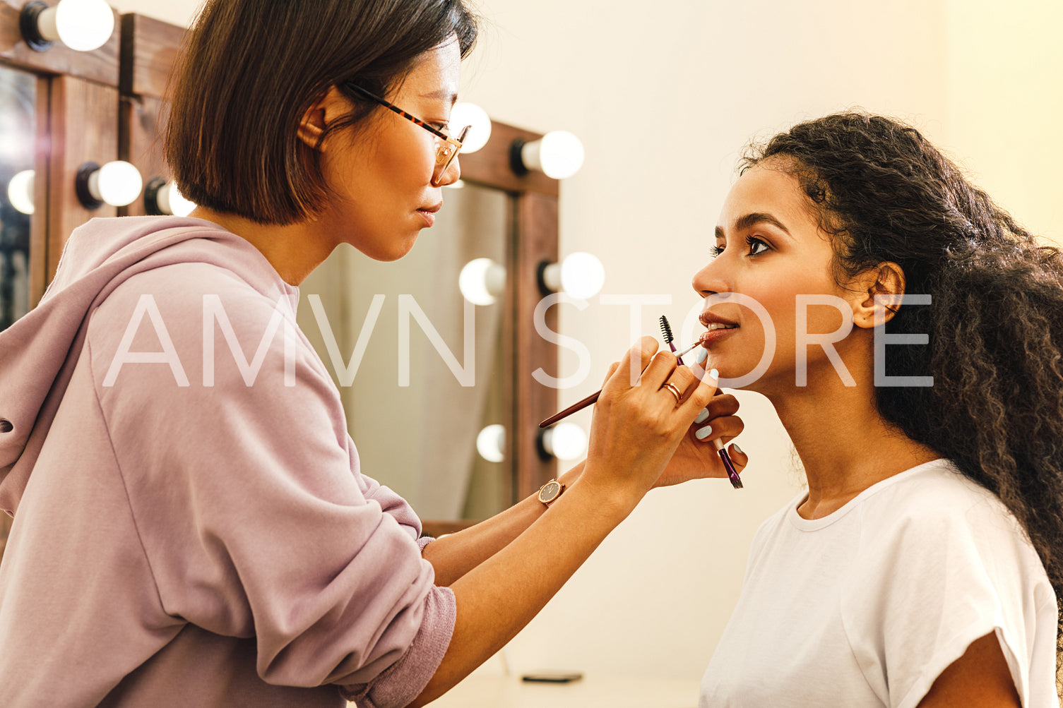 Side view of a makeup artist applying lip paint with a brush	