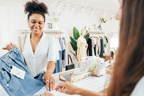 Young stylish woman buying clothes in boutique standing at the checkout counter