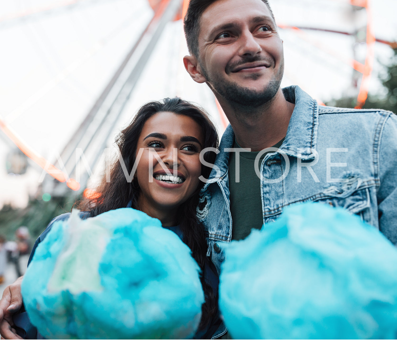 Young happy couple standing together holding blue cotton candy