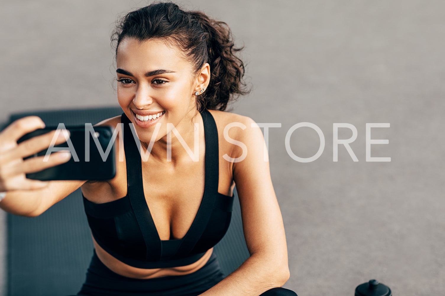 Close up of a beautiful smiling woman holds a cell phone and taking selfie after training	