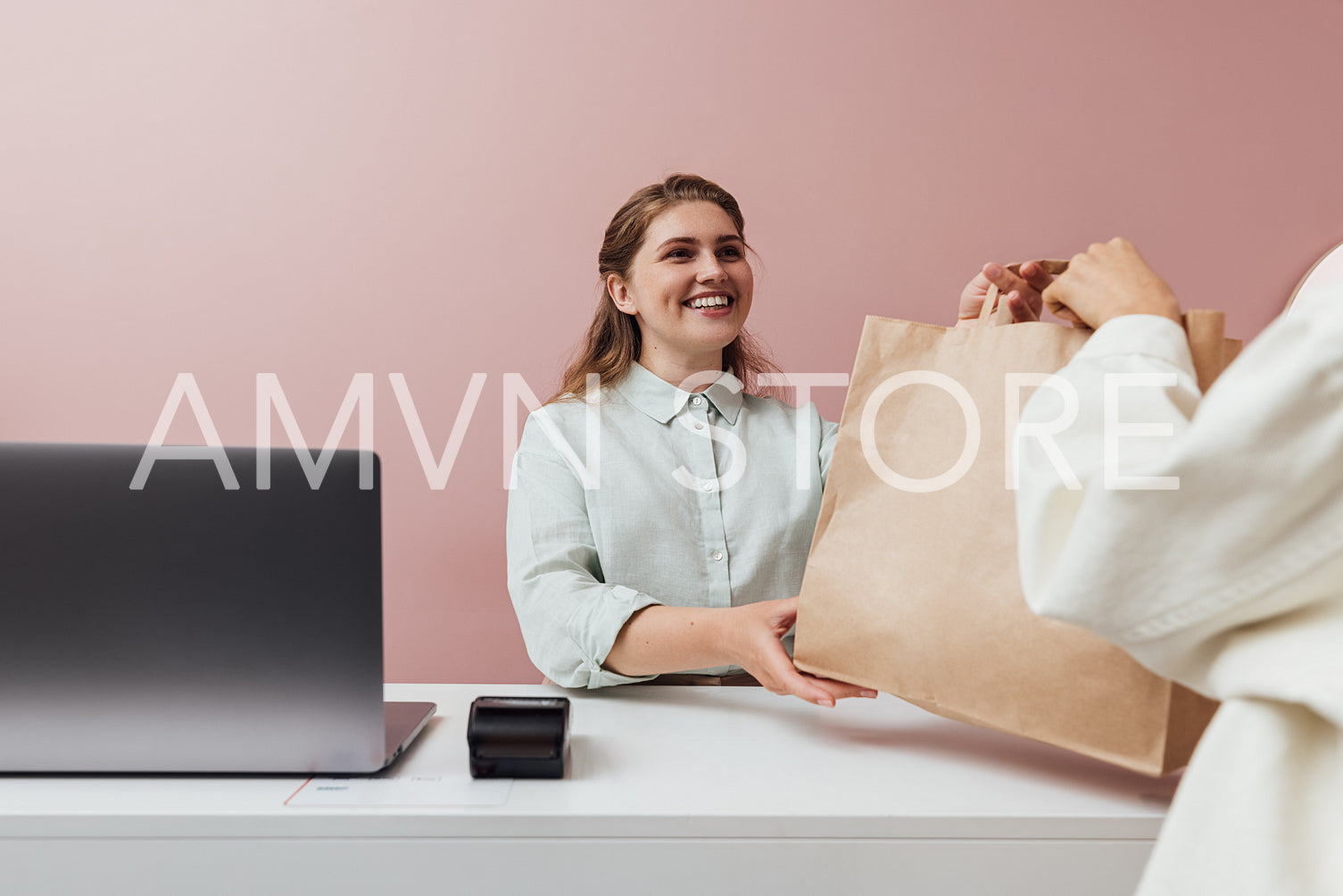 Clothing store owner giving a shopping bag to customer. Unrecogn