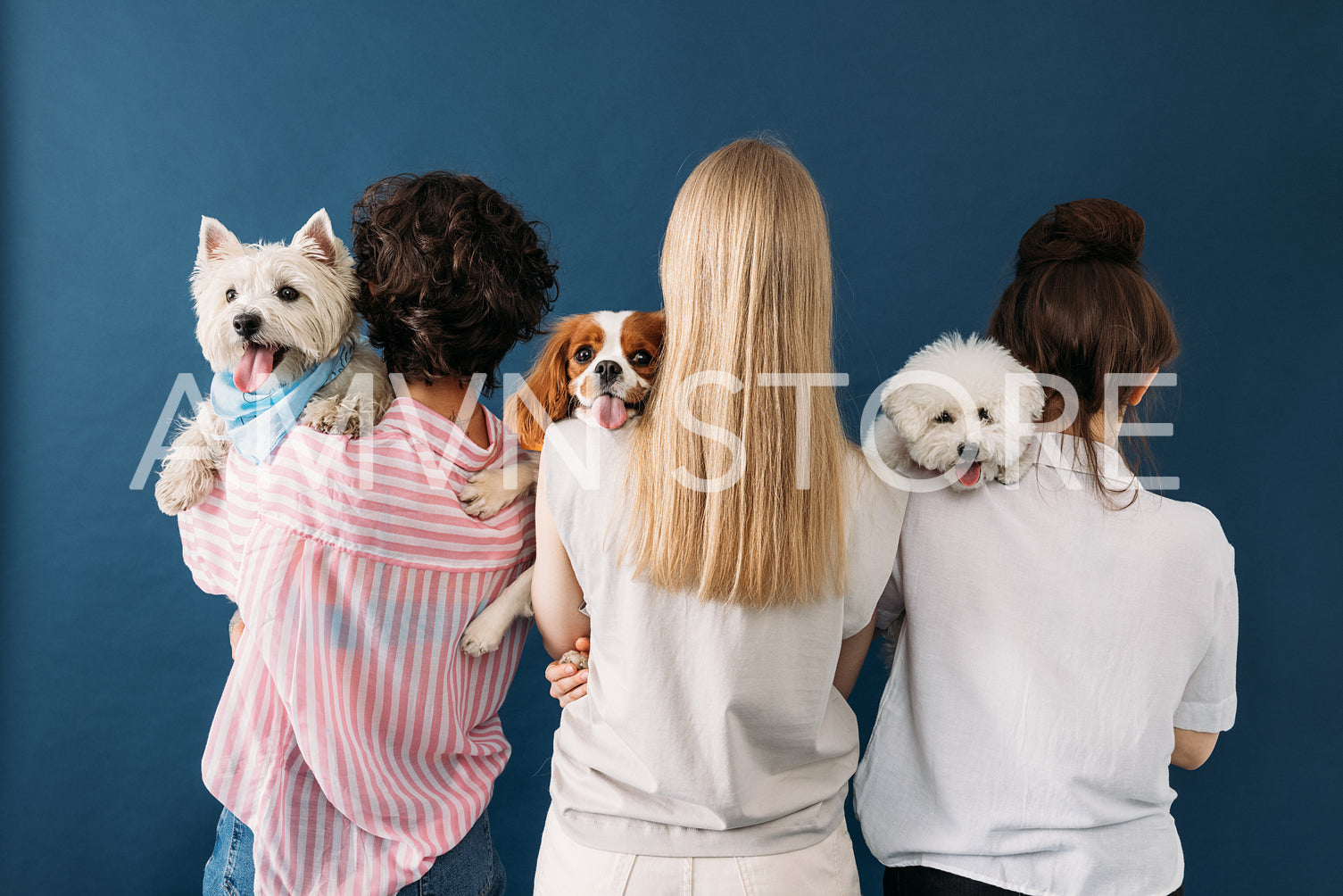 Back view of a three woman holding their dogs on shoulders while