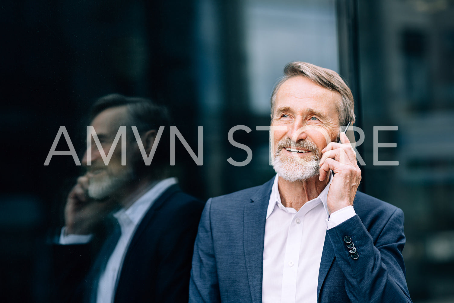 Smiling senior man making call outdoors standing at an office building	