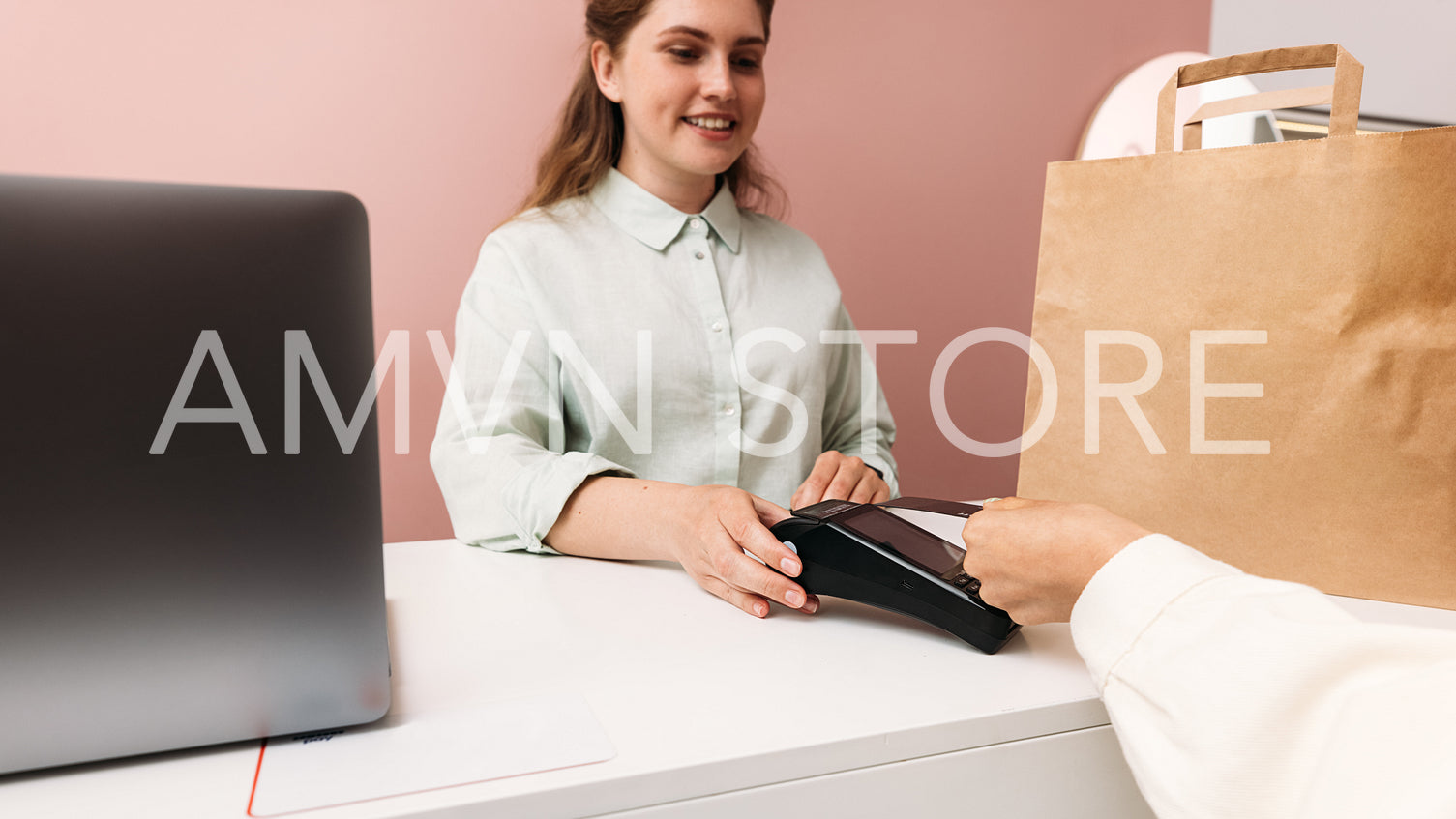 Smiling boutique owner holding pos terminal while customer makin