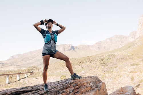 Happy female hiker in sportswear standing on a rock enjoying the view