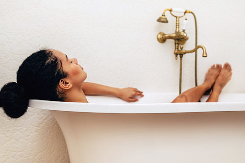 Female relaxing in bathtub with eyes closed