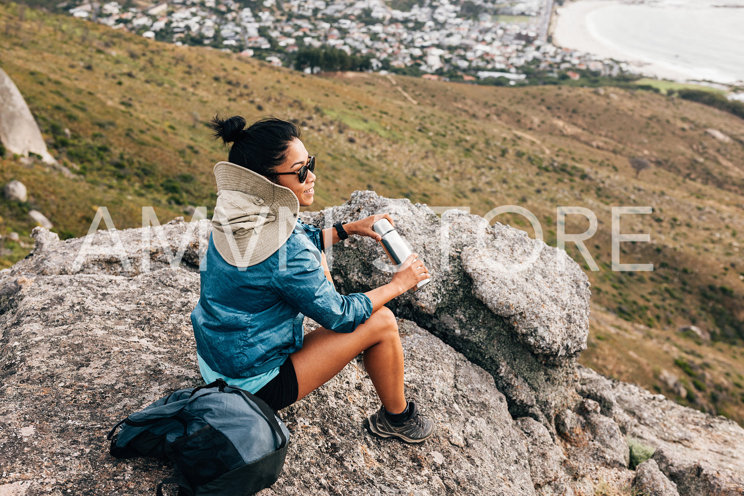 Woman hiker relaxing during hike sitting on a stone holding thermos