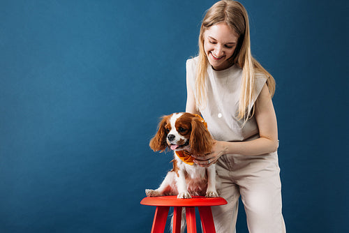 Pet owner standing in the studio. Little dog sitting on a red ch