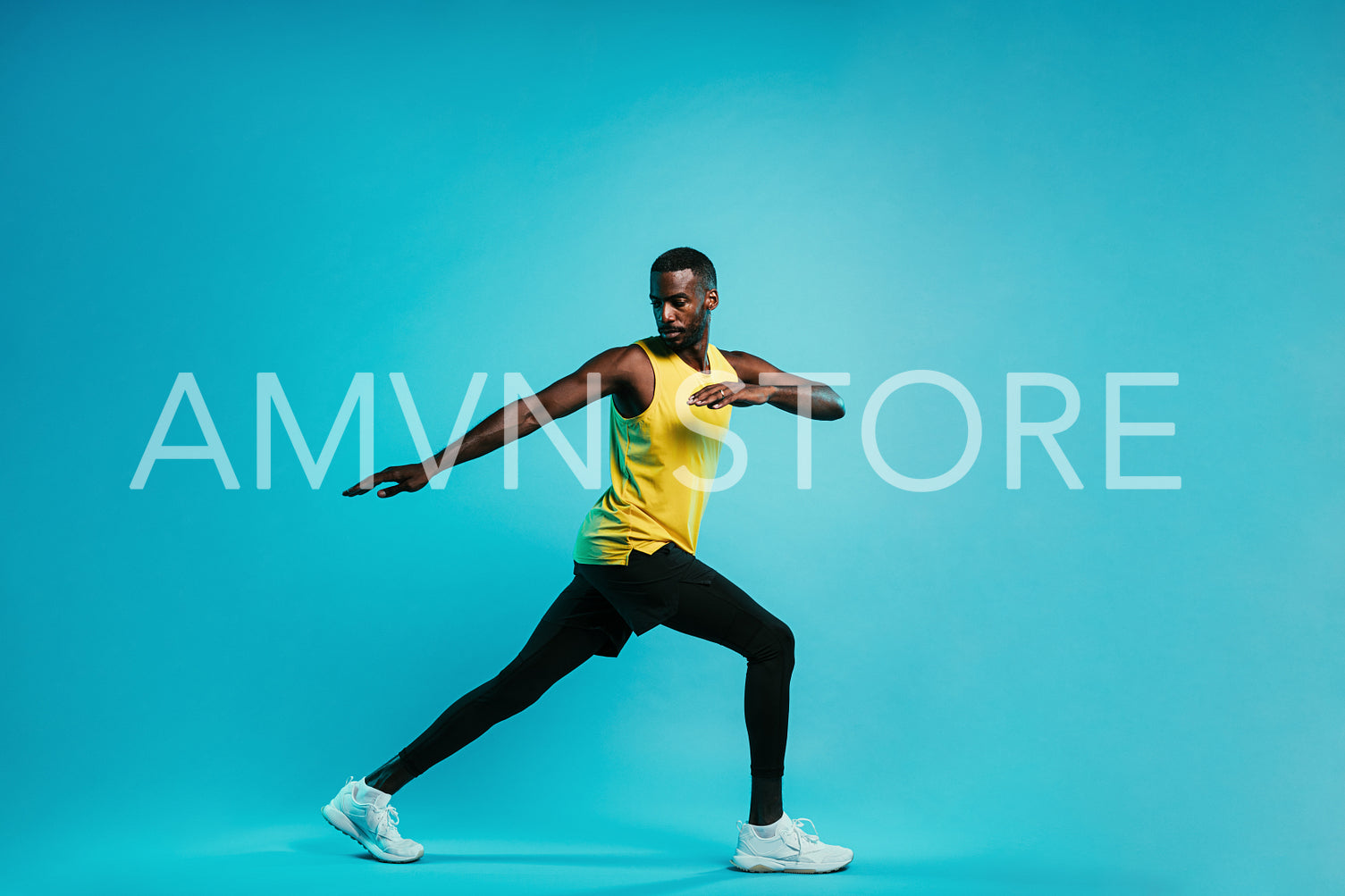 Young sportsman standing on blue background. Athlete warming up his body during a workout.