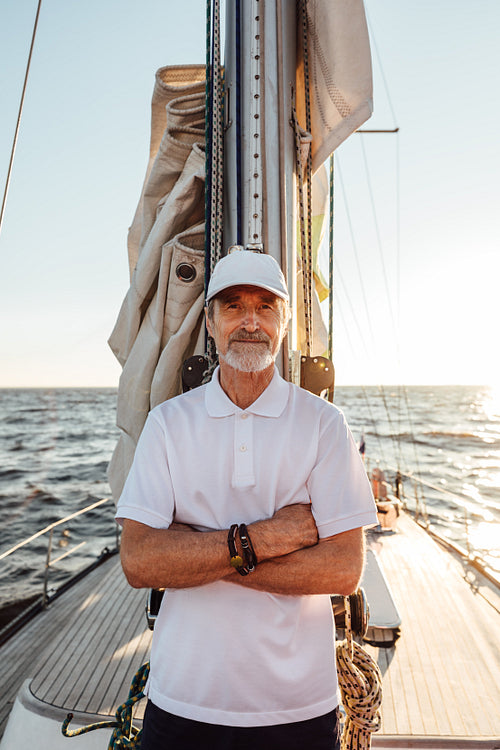 Portrait of a mature captain standing on his yacht at mast with crossed arms