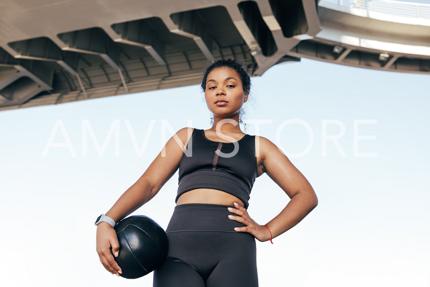 Low angle shot of a confident sportswoman with medicine ball standing outdoors under a bridge