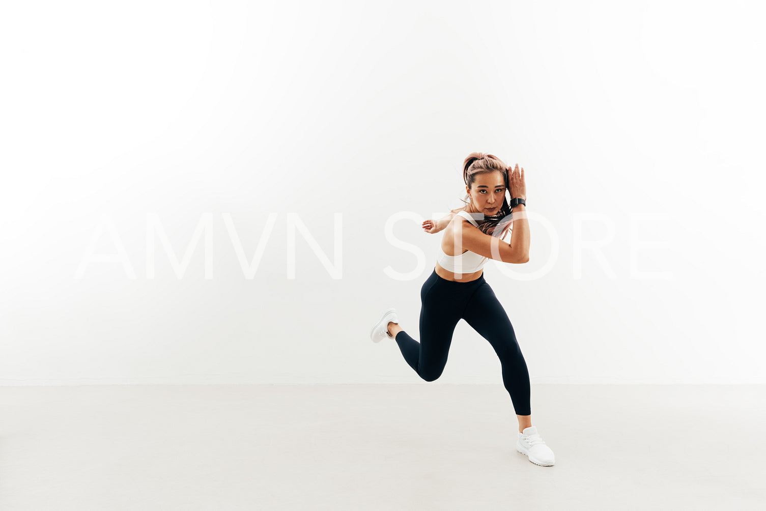 Asian woman doing warming up exercises against white wall indoors