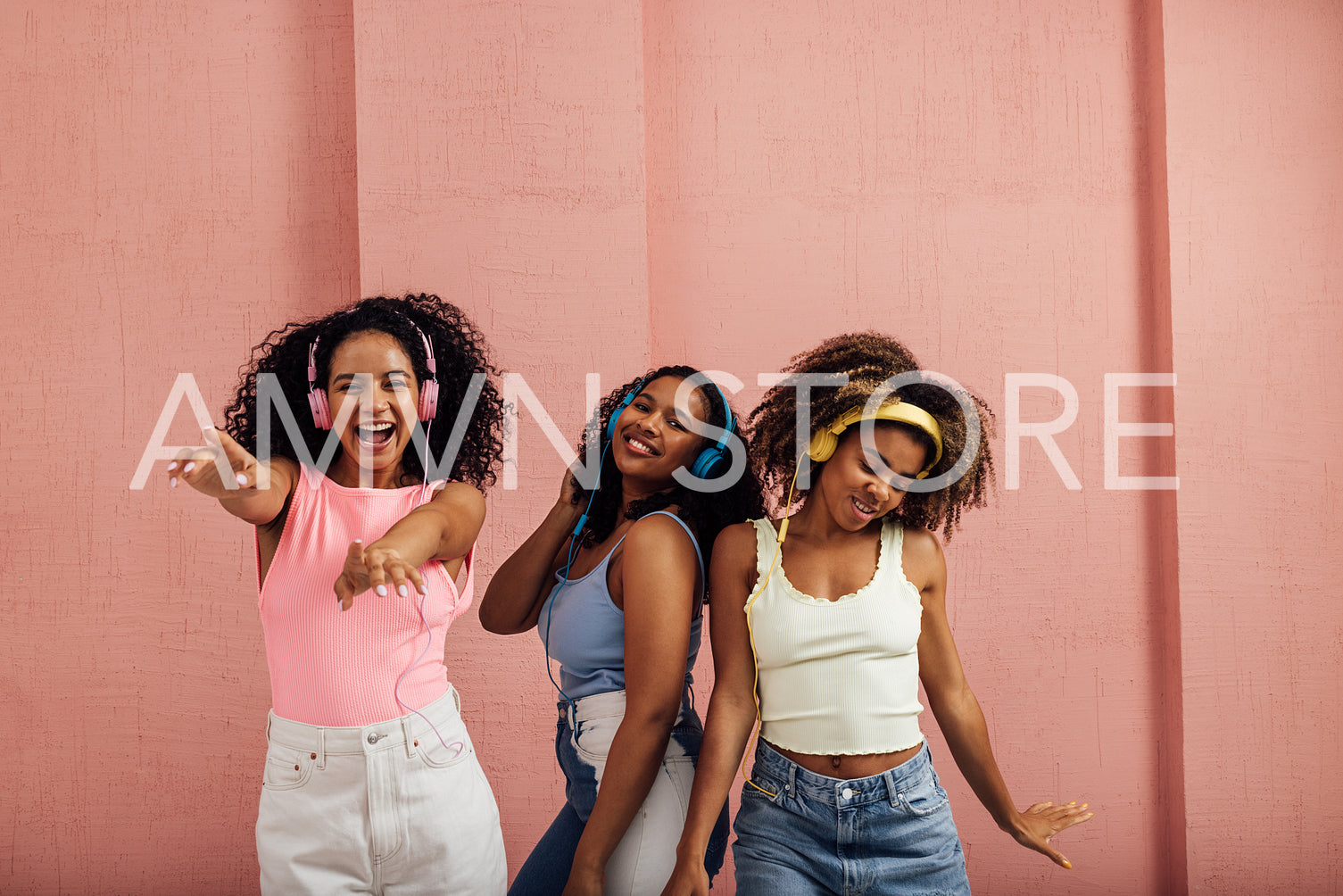 Group of young women dancing together while listening to music b