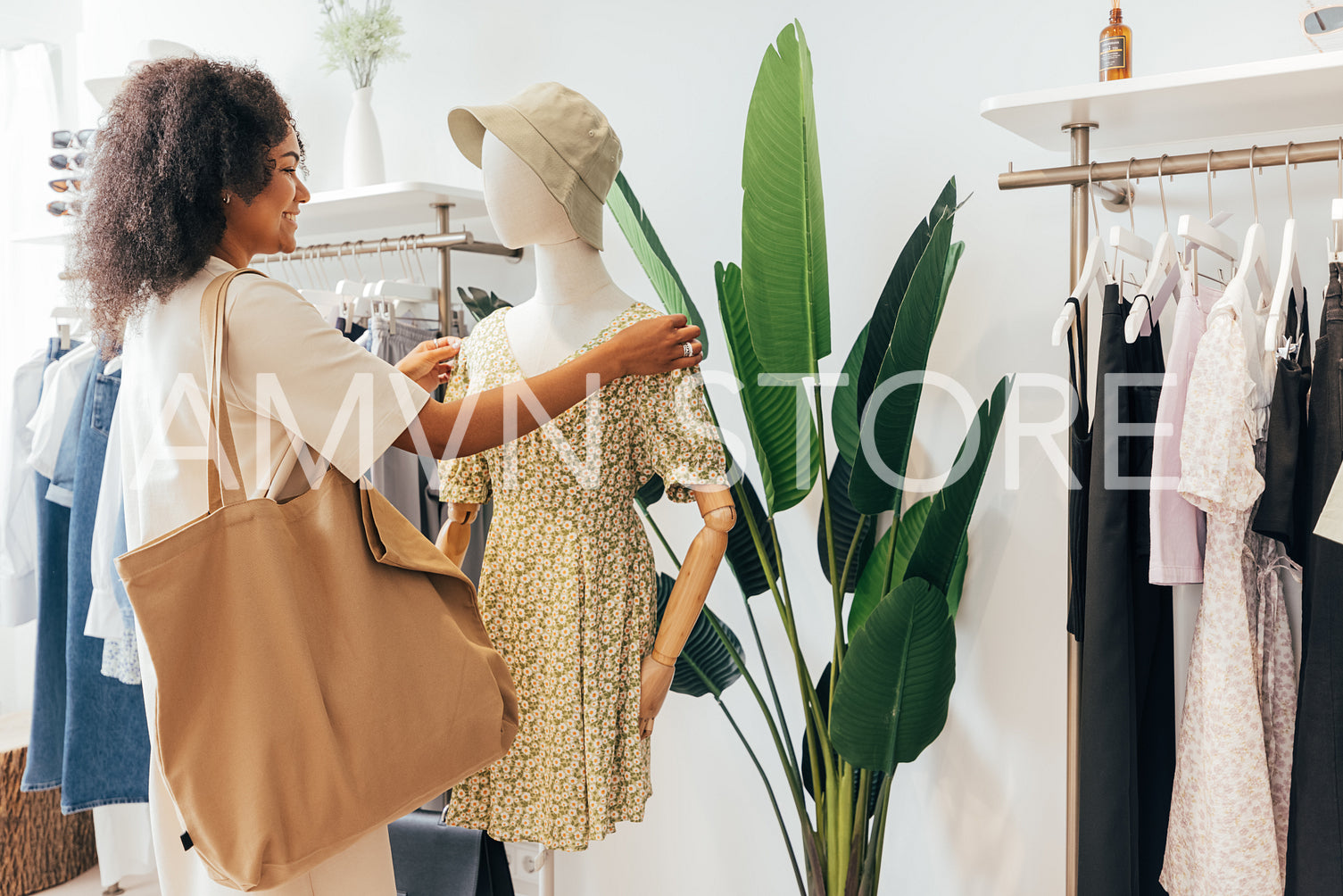 Stylish woman with big shopper bag standing at a mannequin in a boutique while looking new clothes