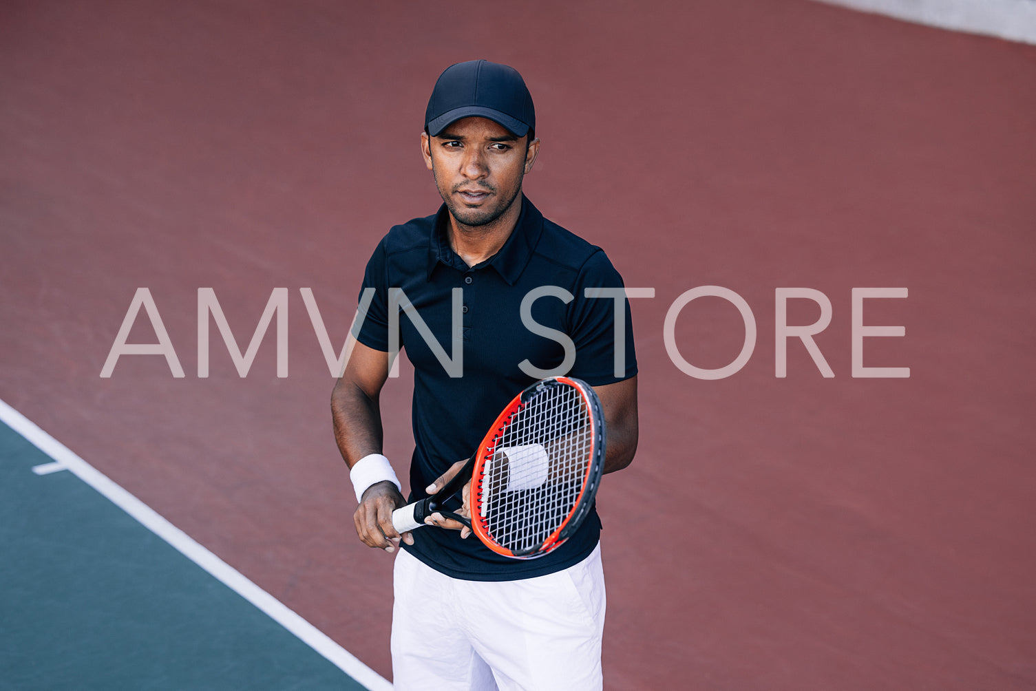 Portrait of a young tennis player with a racket standing on a hard court