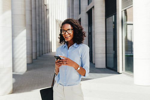 Woman wearing eyeglasses holding a smartphone in hands