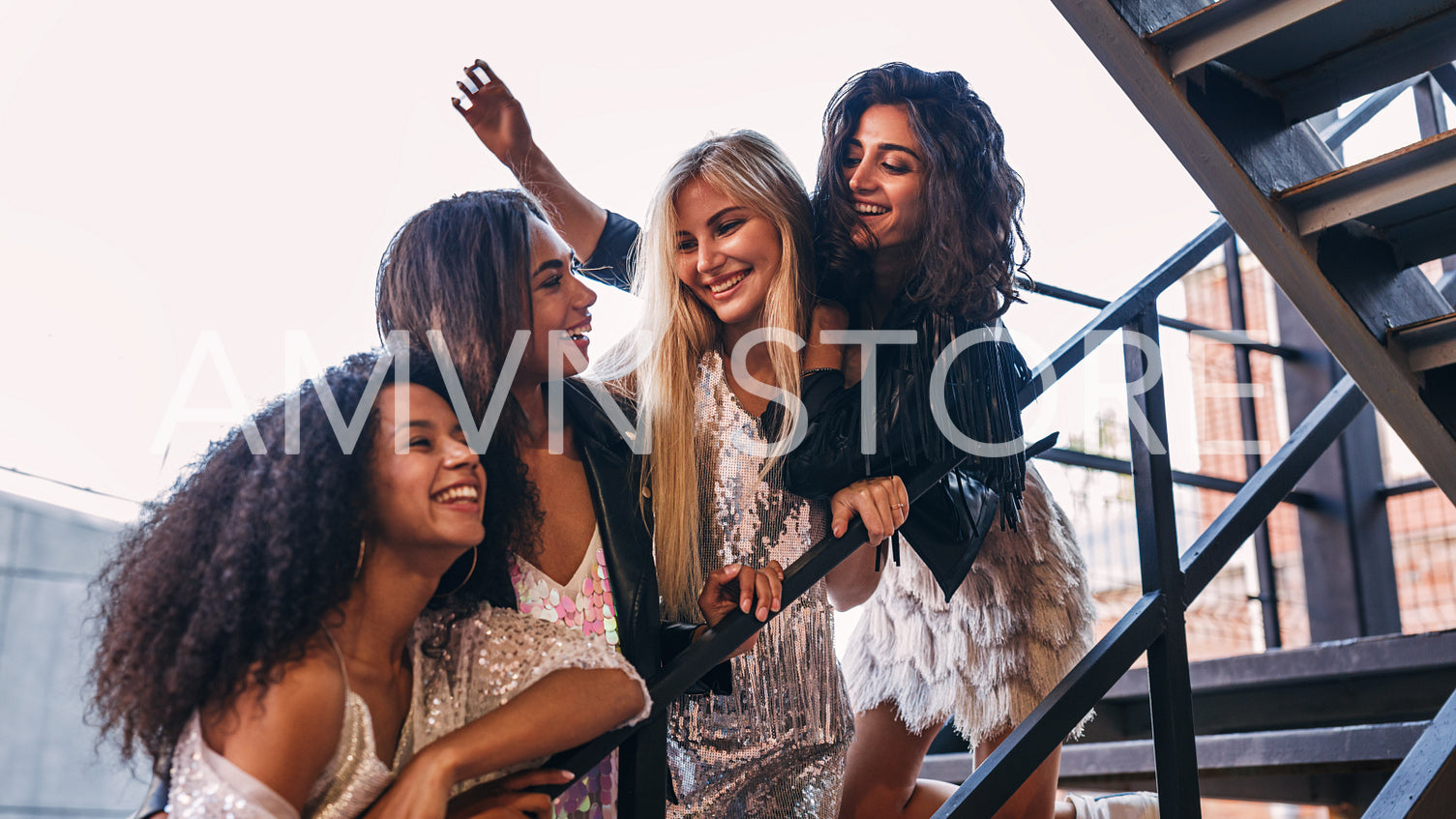 Laughing friends hugging together on the staircase in the city	