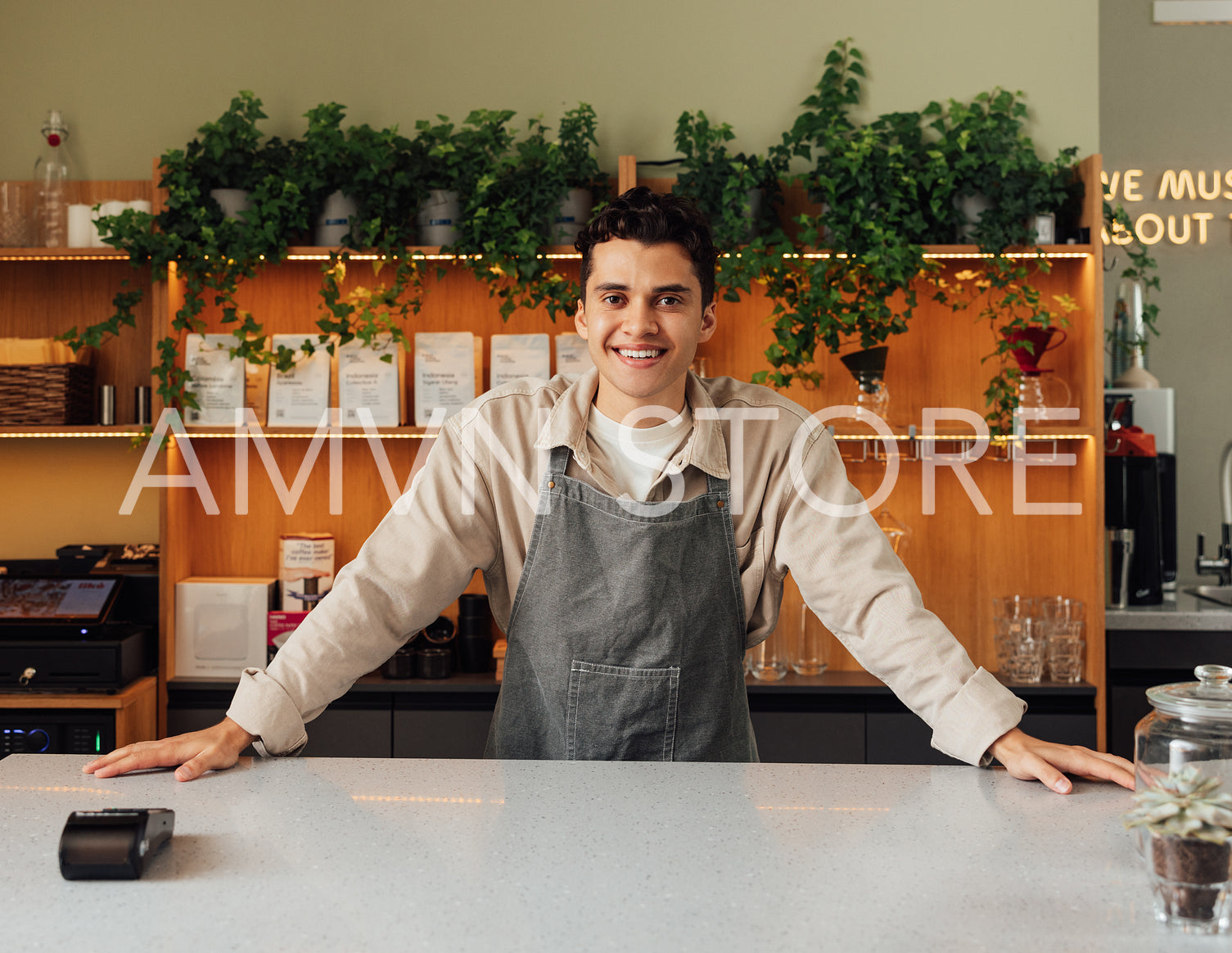 Smiling coffee shop owner at the bar counter. Confident barista looking at camera.