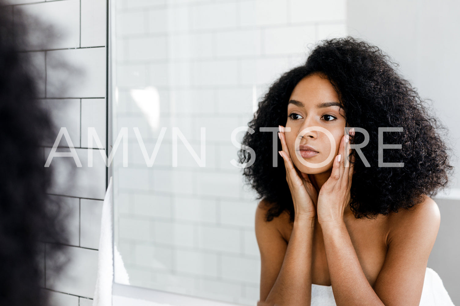 Mixed race woman massaging her face and looking at a mirror	