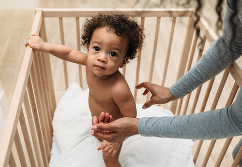 Portrait of baby boy standing in crib