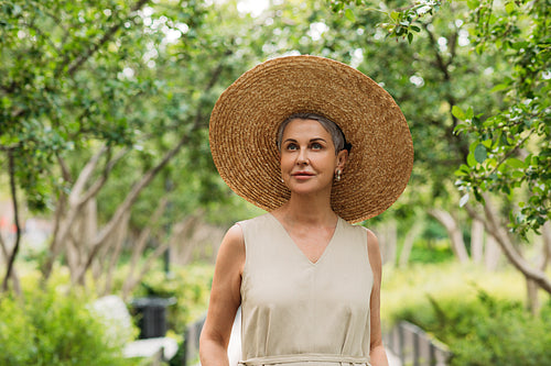 Senior woman wearing big straw hat walking in park