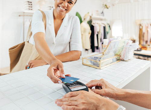 Stylish woman paying via credit card at a counter in a small clothing store