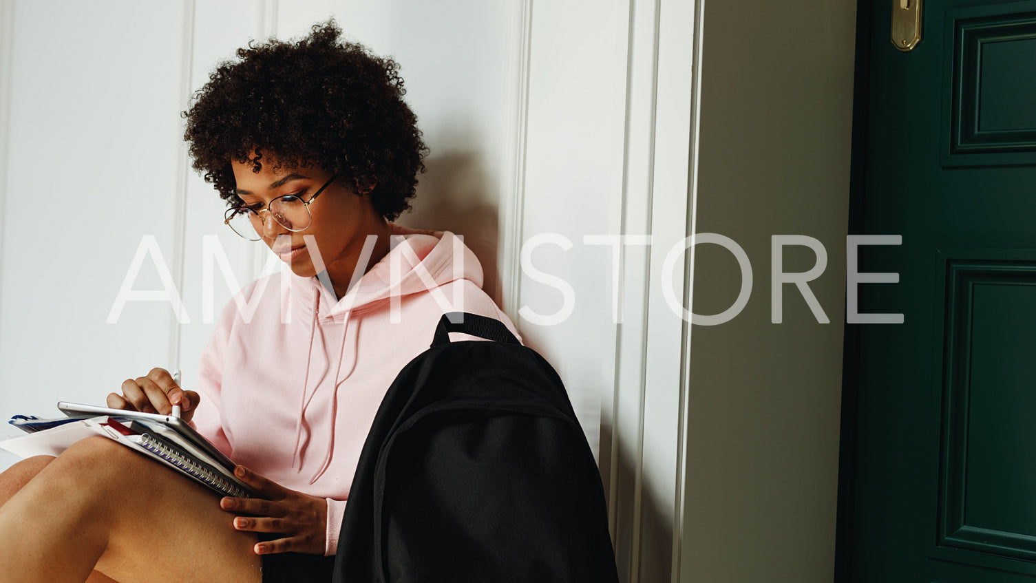 Young African American girl studying indoors, sitting at wall	