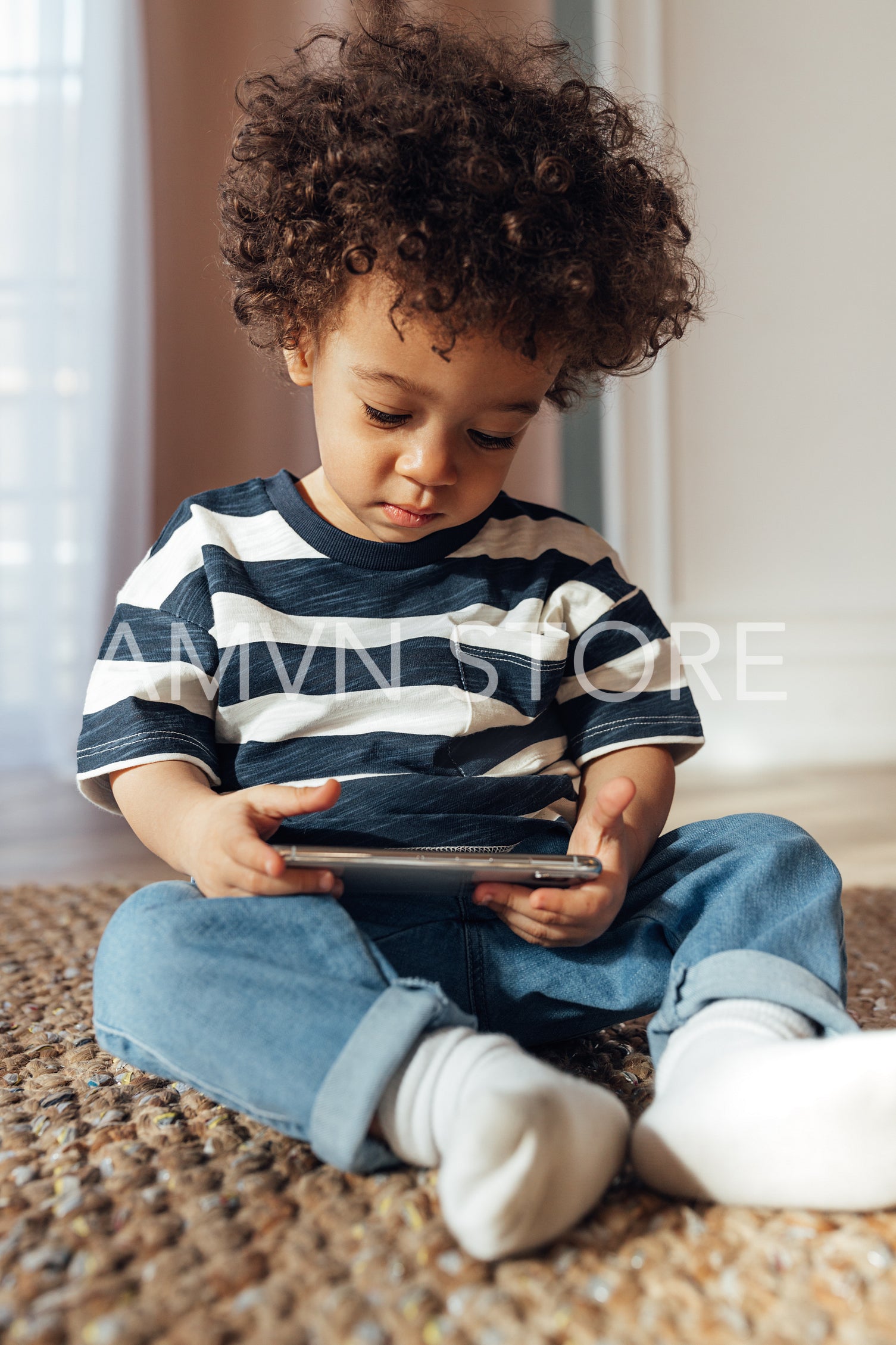 Little boy sitting indoors with a smartphone in his hands