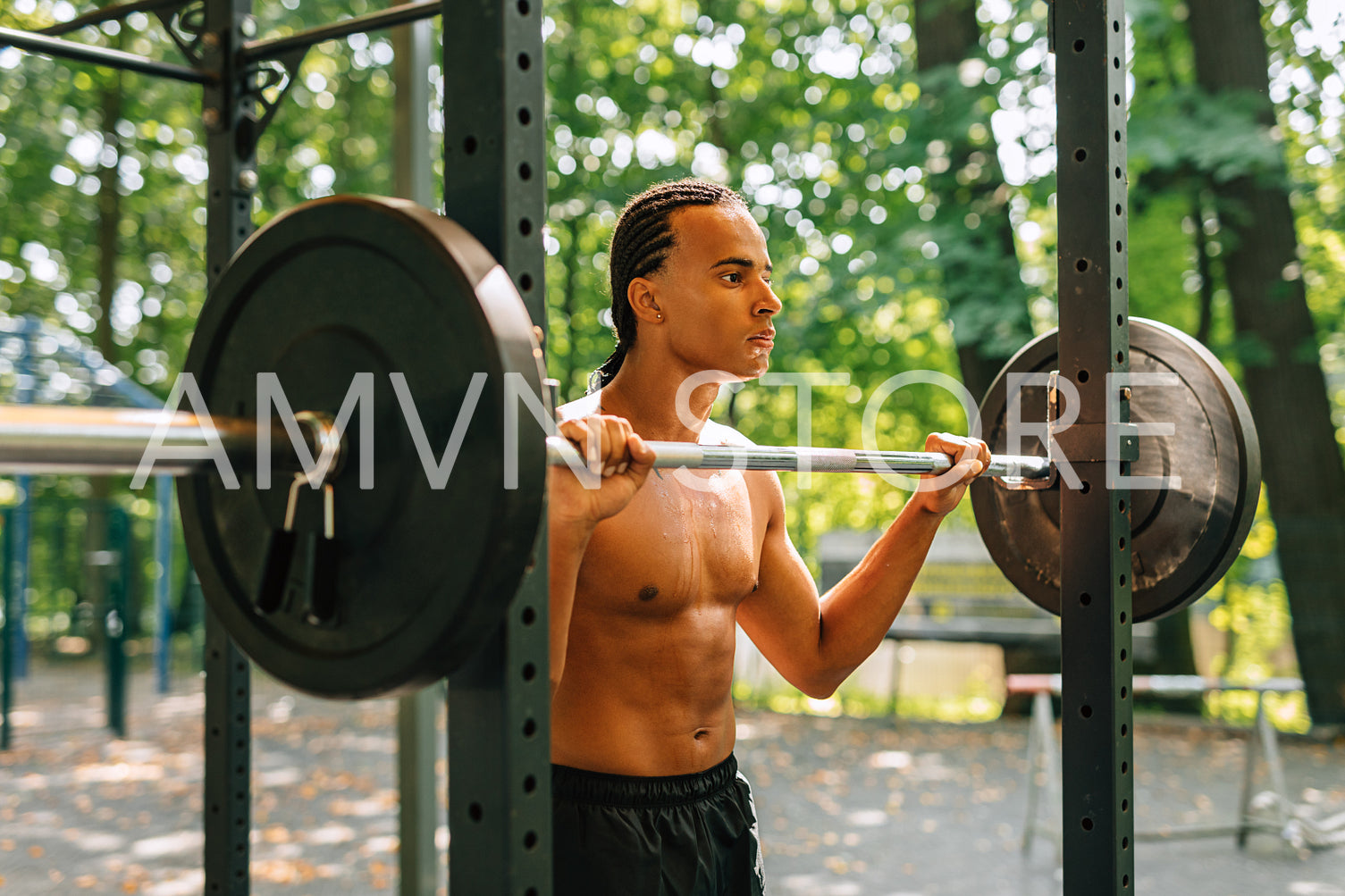 Young man leaning over weight bar after training outdoors	