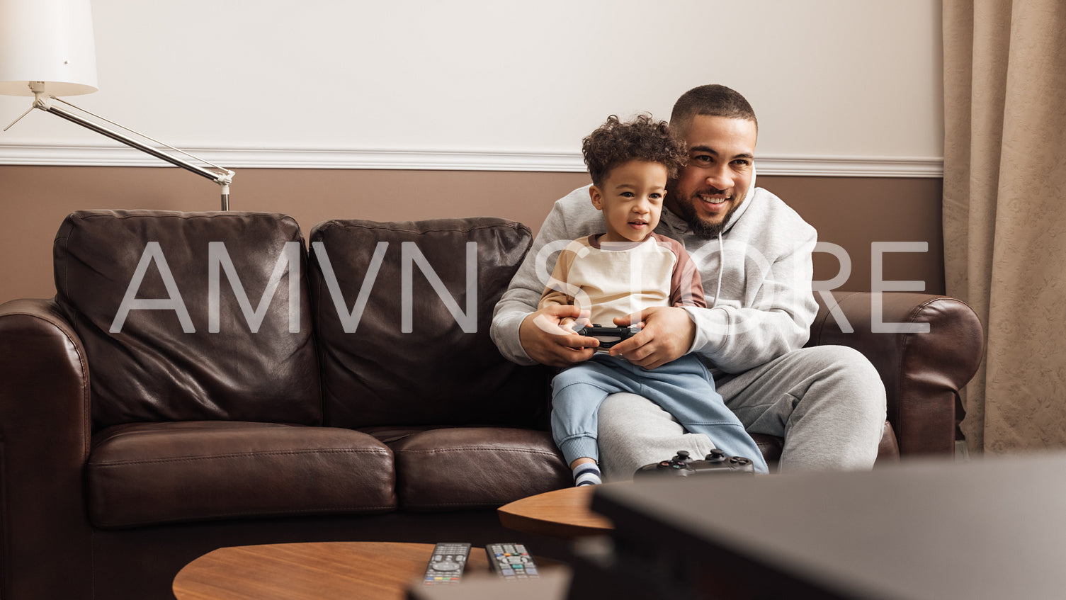 Little boy sitting on the hip of his father and holding joystick