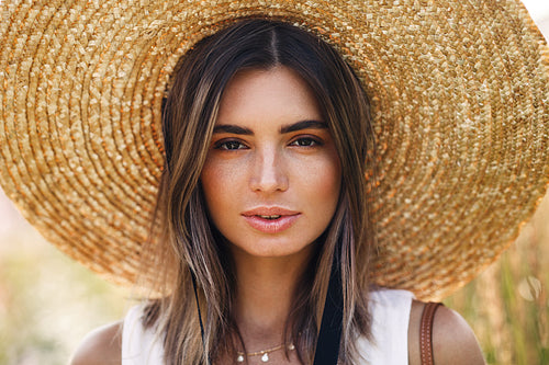 Close up portrait of a beautiful woman in straw hat looking at camera