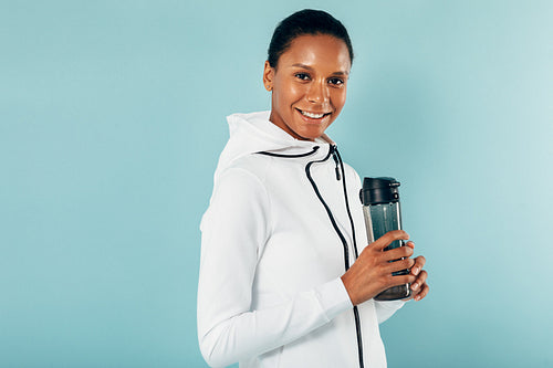 Happy young woman taking a break after exercising holding a water bottle