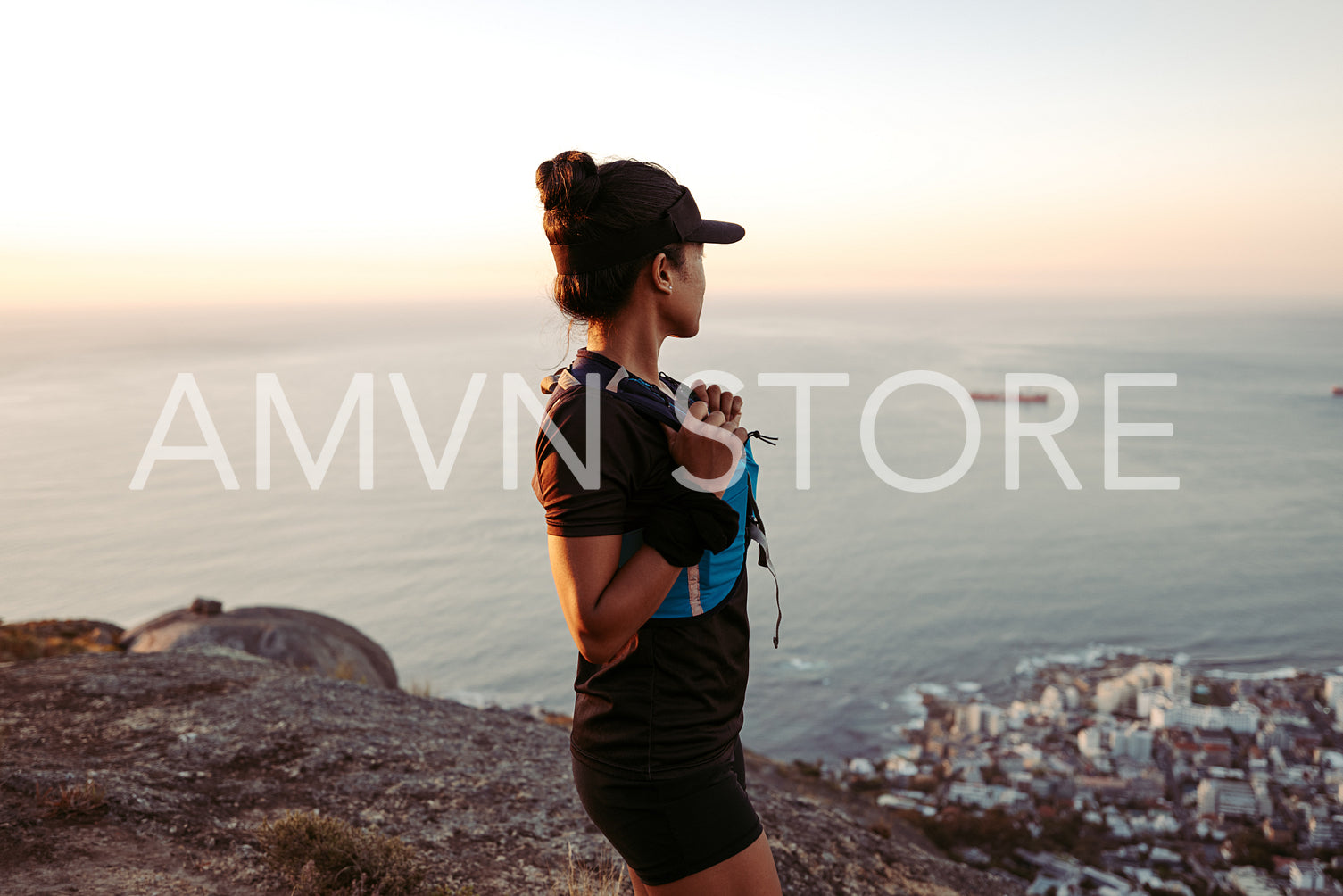 Side view of female hiker looking at the ocean at sunset from the top of the mountain