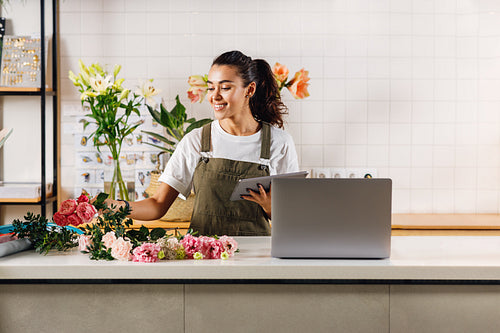 Woman holding a digital tablet and selecting flowers for a bouquet