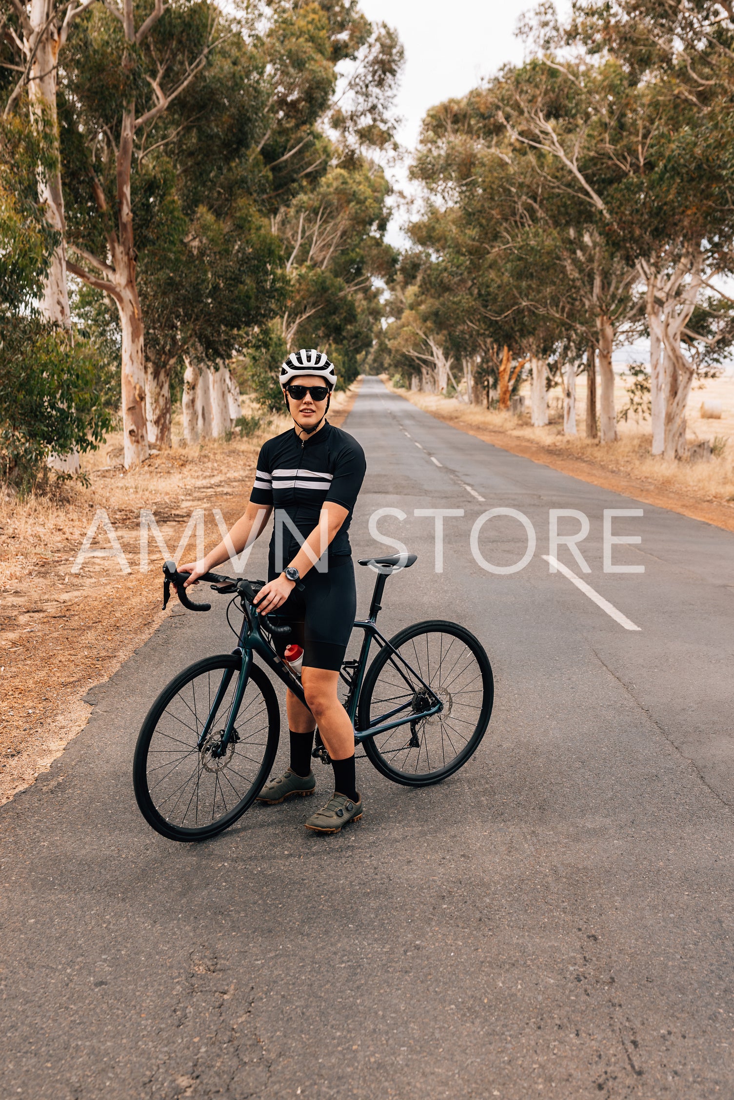 Professional woman cyclist standing with bike on a road