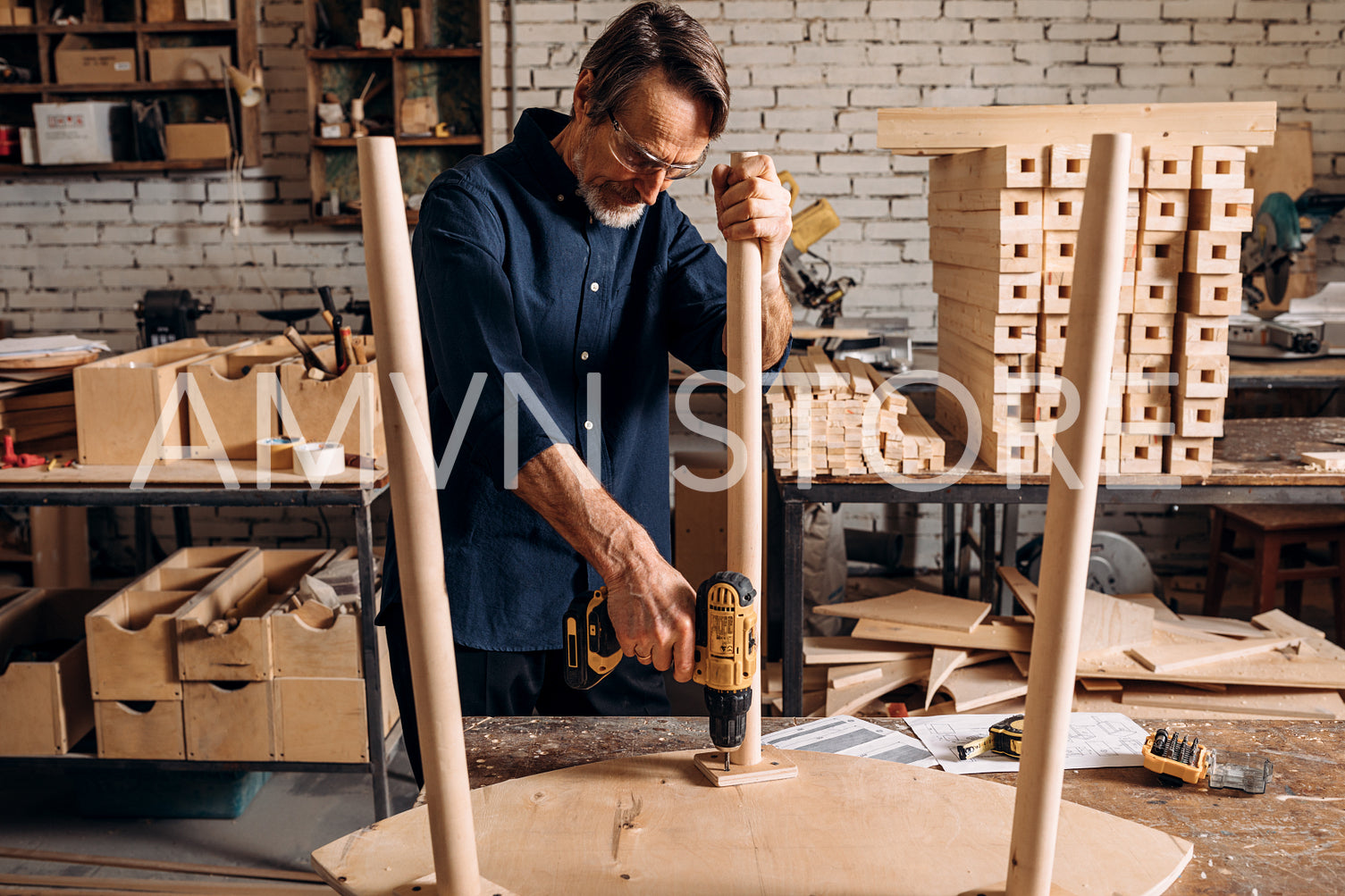 Carpenter drilling hole in wooden a table	