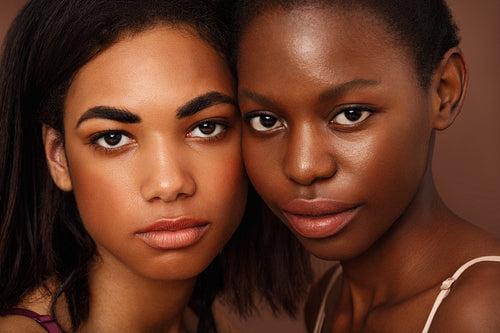 Close up portrait of two beautiful African American women looking at camera in studio