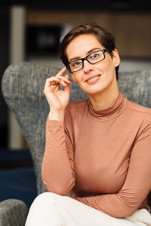 Portrait of a beautiful businesswoman in casuals looking at camera and holding eyeglasses