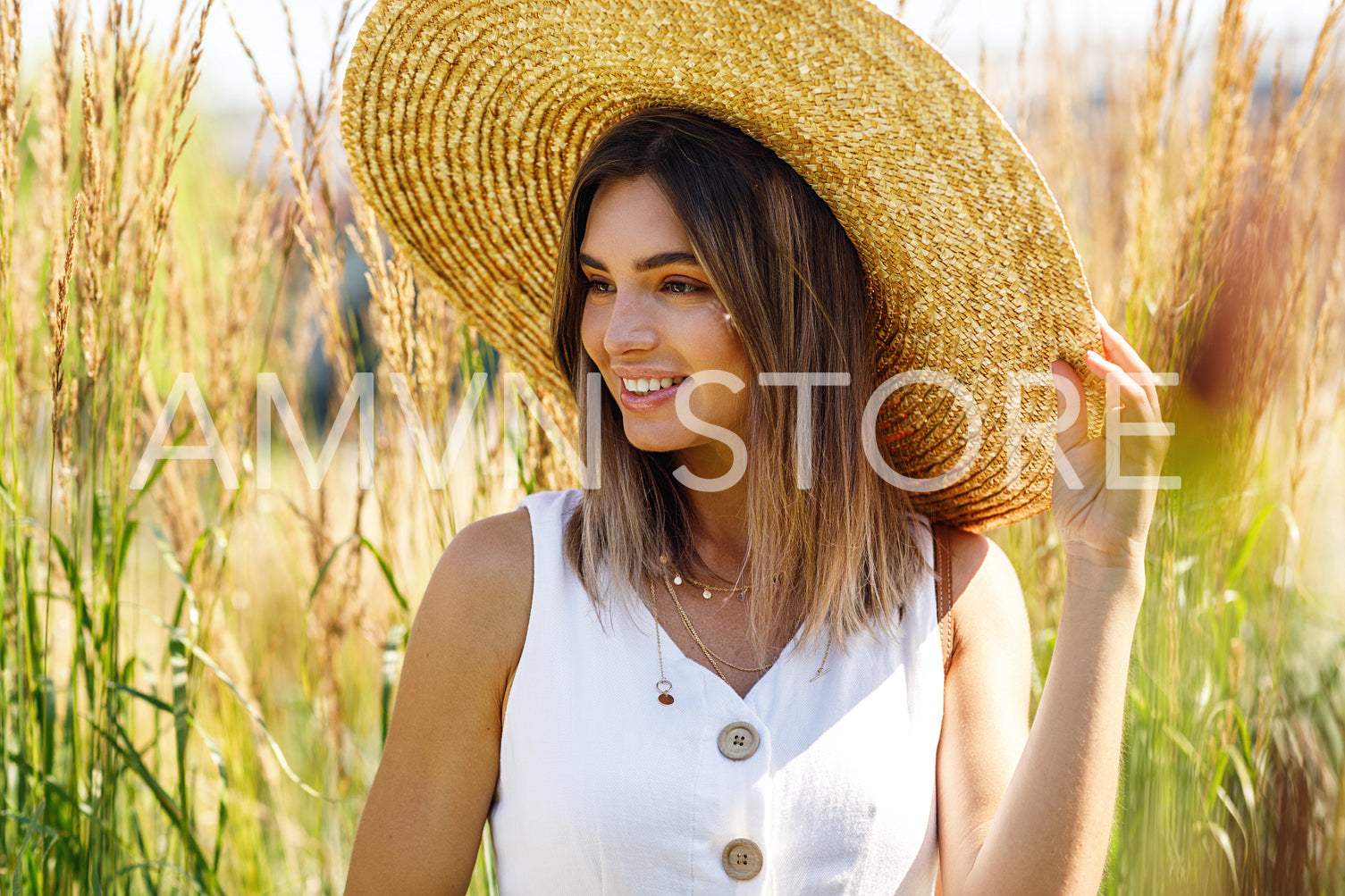 Portrait of a young smiling woman wearing a big straw hat outdoors	