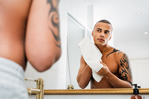 Young handsome man drying his face with white towel after shaving