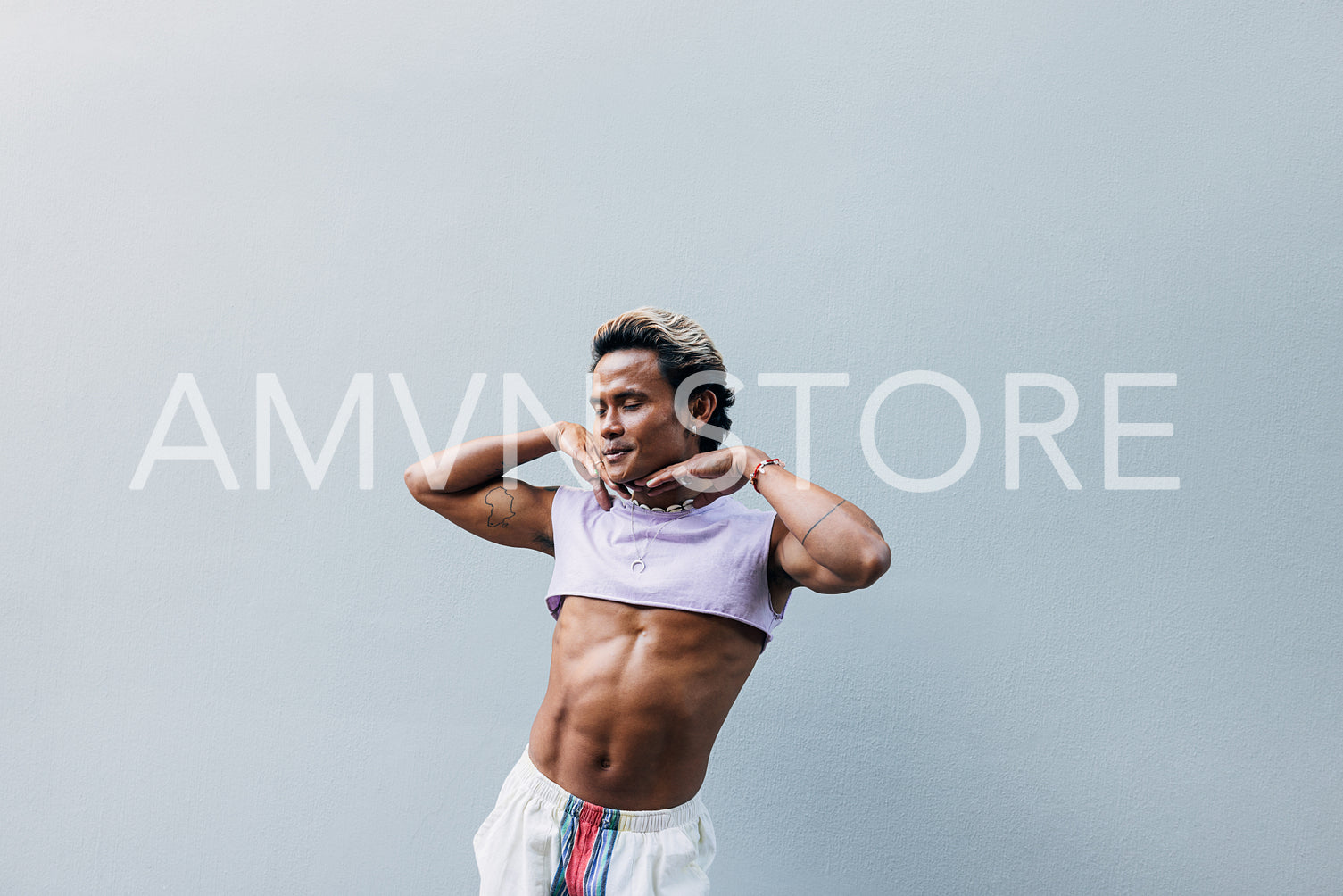 Young handsome man posing against grey wall in stylish clothes